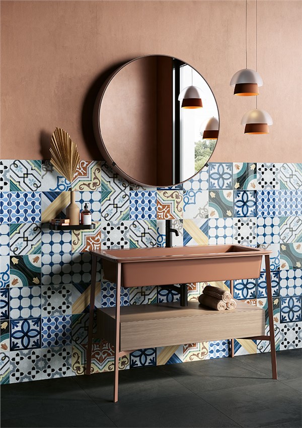 Bagno con rivestimento decorato a motivi blu, consolle in legno e specchio tondo