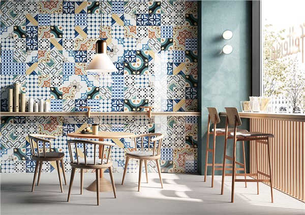 Locale con parete rivestita in cementine decorate, tavoli e sgabelli