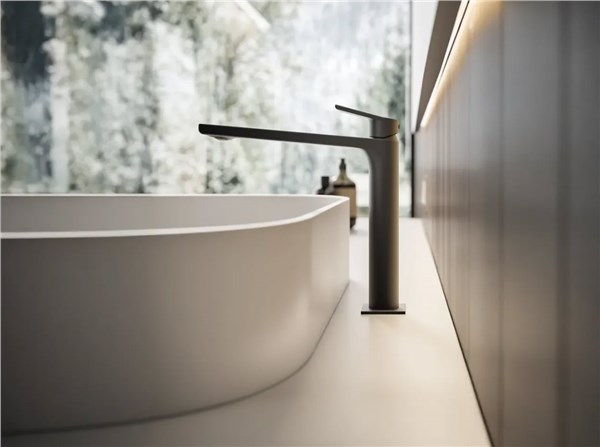 Miscelatore nero su lavabo bianco davanti a una parete effetto marmo