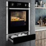 Forno da incasso con cassetto scaldavivande aperto in una cucina in legno