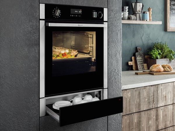Forno da incasso con cassetto scaldavivande aperto in una cucina in legno