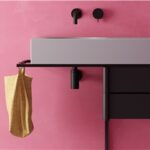 Lavabo integrato su mobile scuro con parete rosa e miscelatori neri