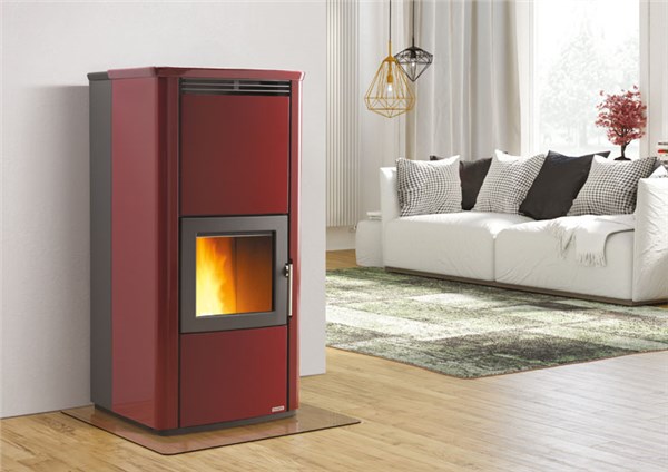 Termostufa a pellet rossa accesa in un soggiorno con divano chiaro
