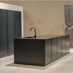 Cucina con isola in travertino e mobili scuri in un ambiente luminoso