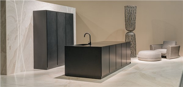 Cucina con isola in travertino e mobili scuri in un ambiente luminoso