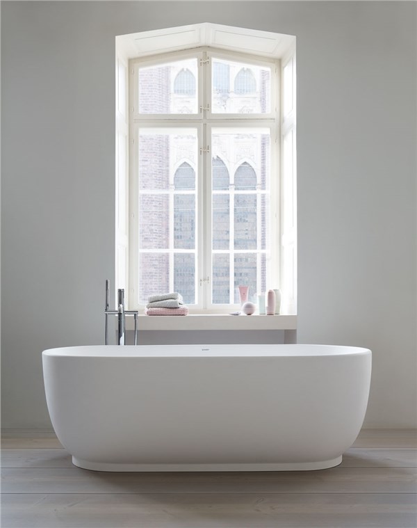 Vasca da bagno freestanding ovale bianca davanti a una finestra ad arco