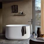 Vasca freestanding tonda bianca in un bagno con parete a doghe e vetrata