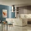 Cucina moderna con isola in marmo, pensili in legno e rivestimento Ceramica Del Conca Premiere, tavolo in vetro e legno.