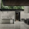 Sala moderna con pavimenti e rivestimenti in marmo della Ceramica Del Conca, scrivania bianca, sedie nere e luce naturale.