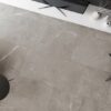 Salotto moderno con grandi piastrelle beige della Ceramica Del Conca, divano chiaro e consolle bianca con TV.