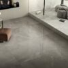 Zona giorno in stile moderno con pavimento effetto marmo grigio lucido di Ceramica Del Conca e sedute in pelle marrone.