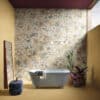 Vasca bianca a libera installazione, rivestimento in ceramica della linea Timeline di Ceramica Del Conca, grande specchio e luce naturale dall’alto.