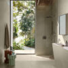 Bagno moderno con doccia walk-in Sensoria Ceramica Del Conca, ampio specchio e porta a vetri che si affaccia sul giardino luminoso.