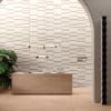 Reception moderna con parete rivestita in Ceramica Del Conca Timeline, bancone in legno chiaro ed eleganti dettagli di design.