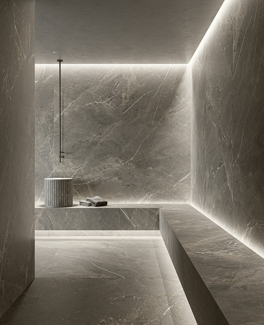 Hammam moderno con piastrelle Marble Edition di Del Conca, lavabo cilindrico in pietra e panca con asciugamani.
