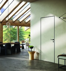 Soggiorno moderno con porte interne a filo muro, tavolo da pranzo, sedie scure e ampie vetrate luminose.